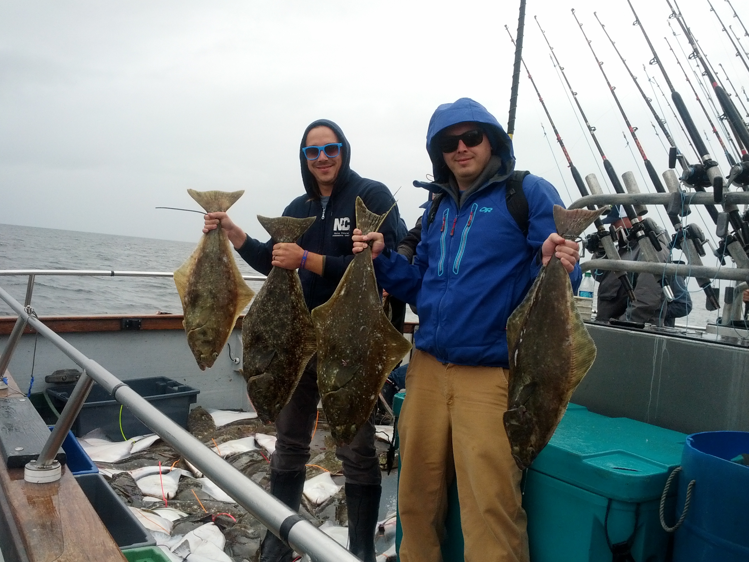 Brothers holding halibut on a boat.