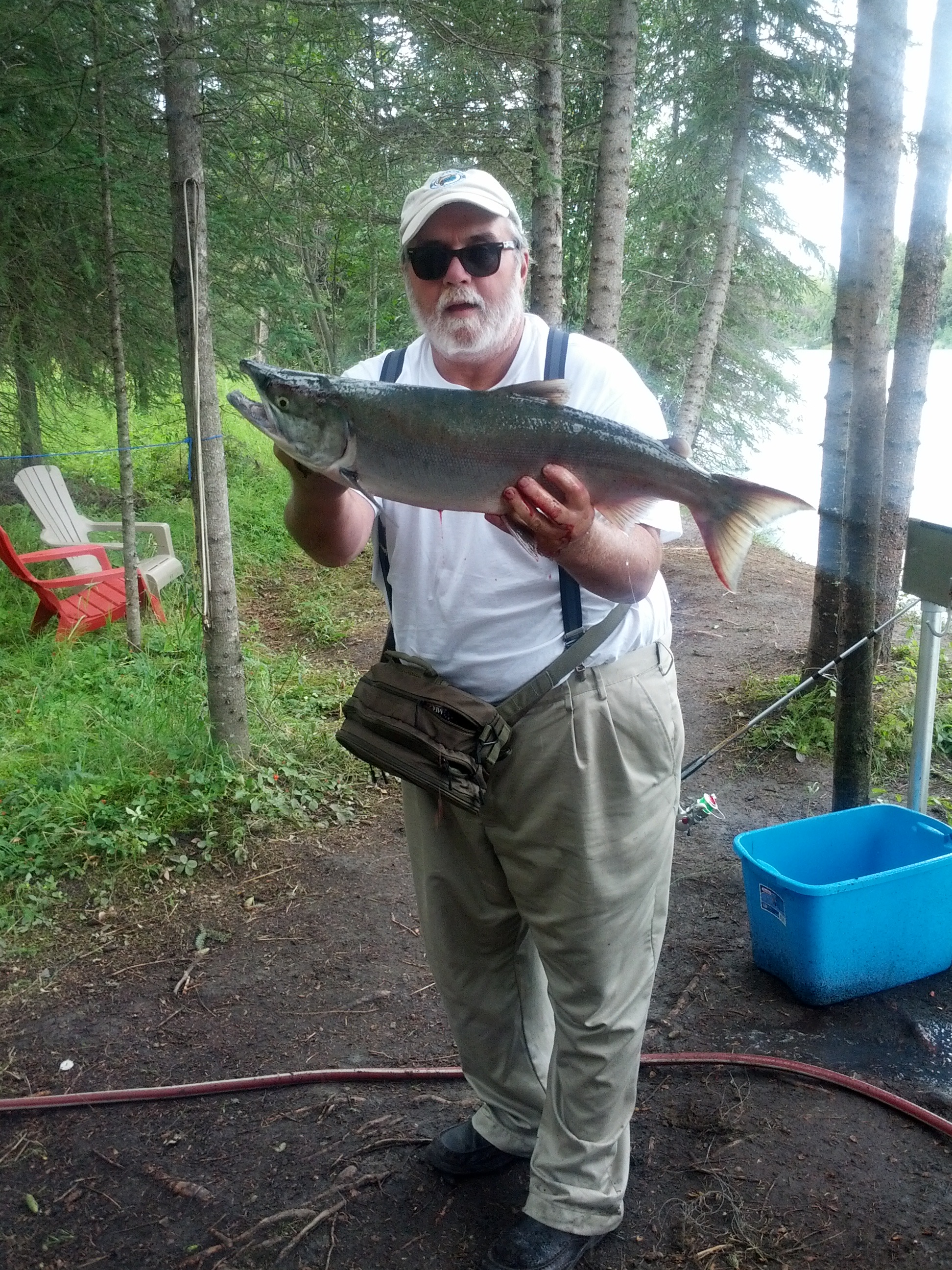 Man posing with a salmon on the river bank.