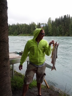 Man in yellow hoody holding a salmon.
