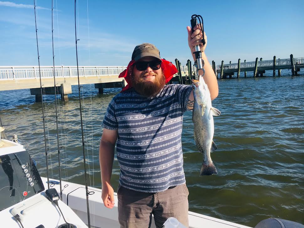 Man smiling with a fish in a striped shirt.