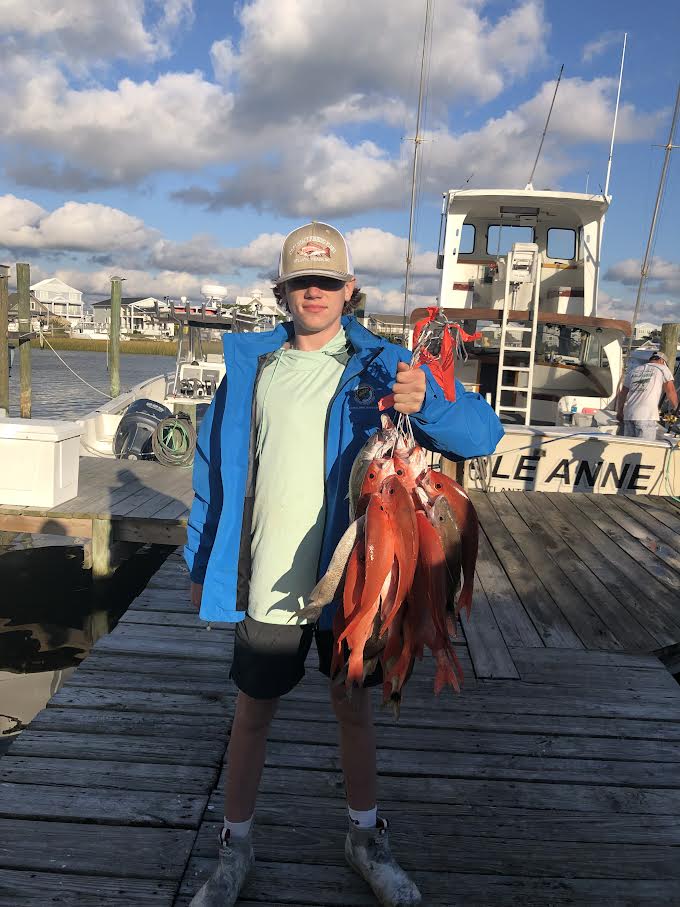 Teenage with a string of fish on the dock.