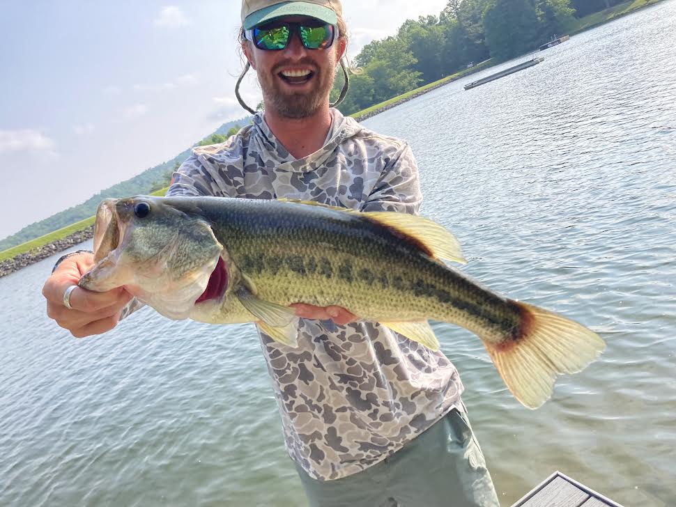Man in camo holds a fish he just caught.