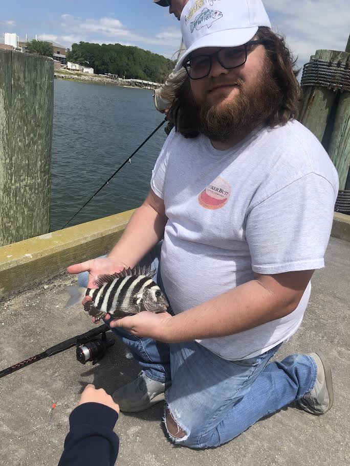 Man holding sheepshead fish on a dock.
