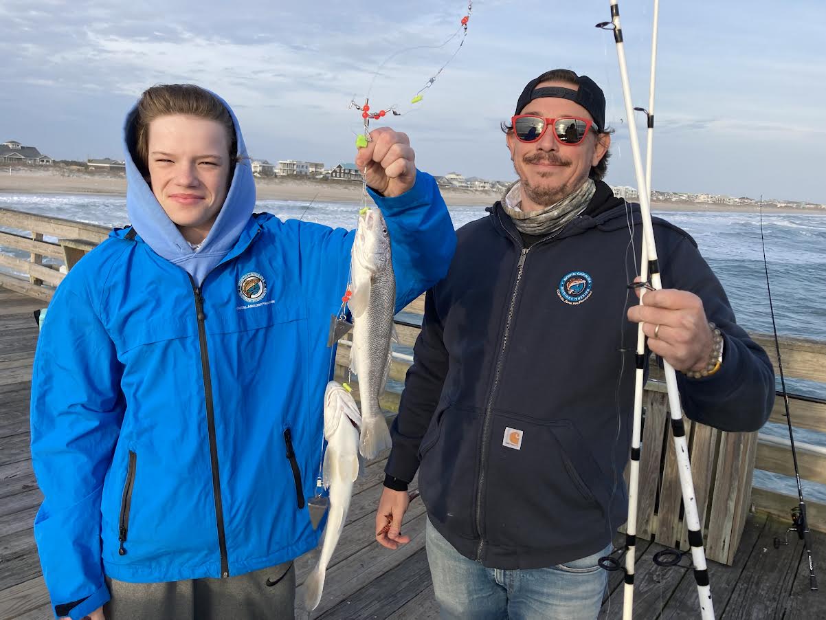 Father and son hold their catch on the pier.