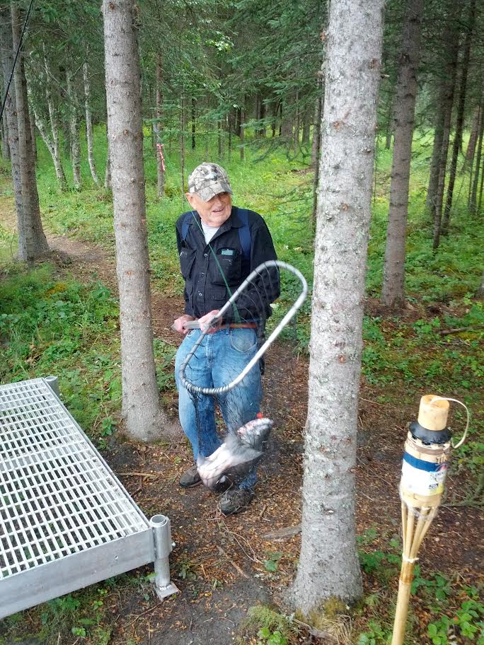 Man with a salmon in a net smiling.