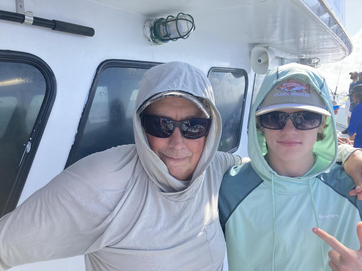 Grandfather and grandson posing for a picture on a charter boat.