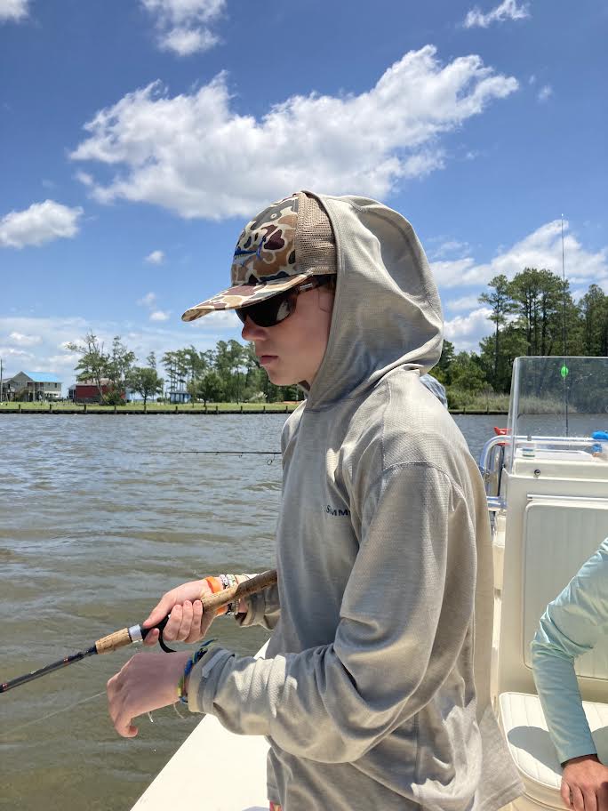Teenager fishing with a hat on.