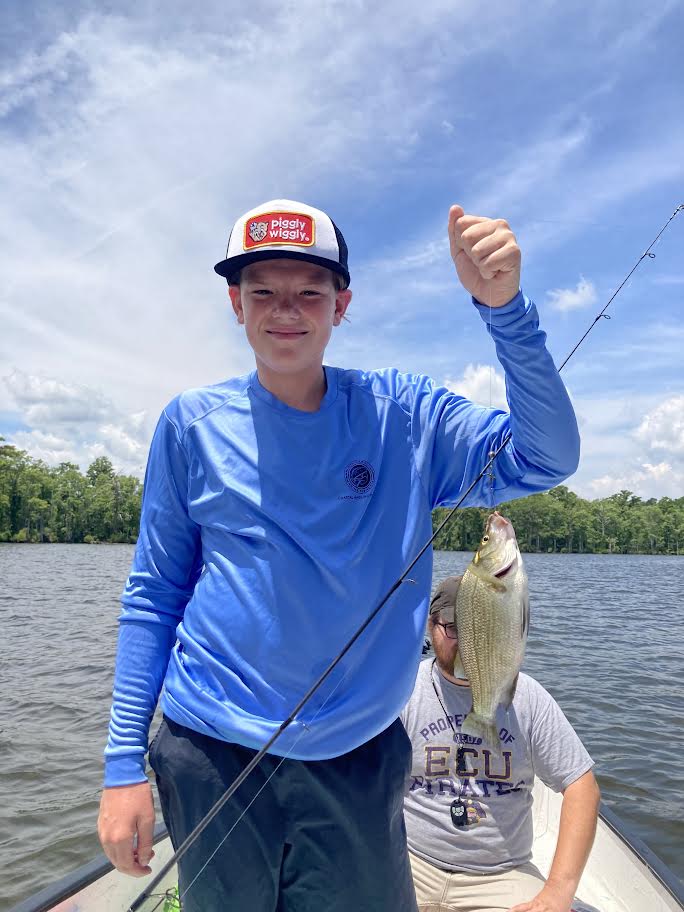 Boy holding his fish on a line in the sound.