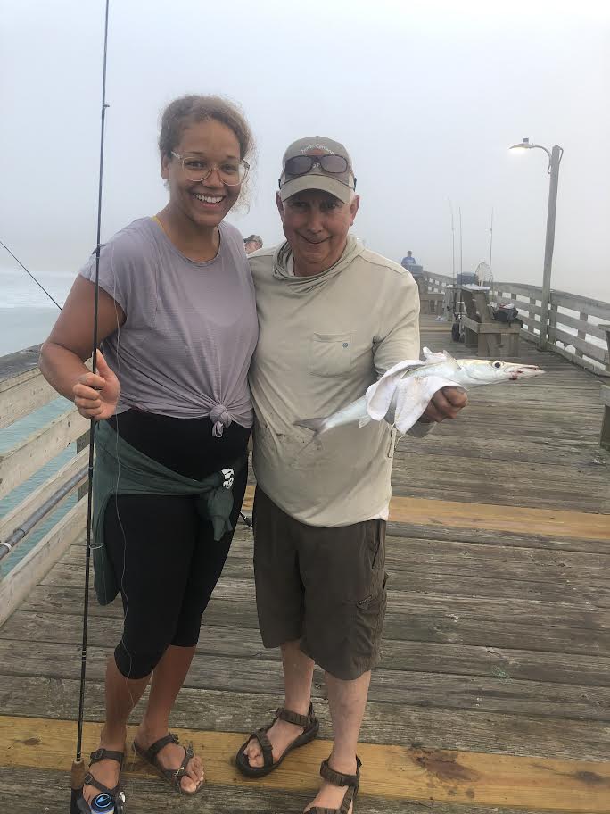 Man on the pier with his daughter-in-law holding a fish.
