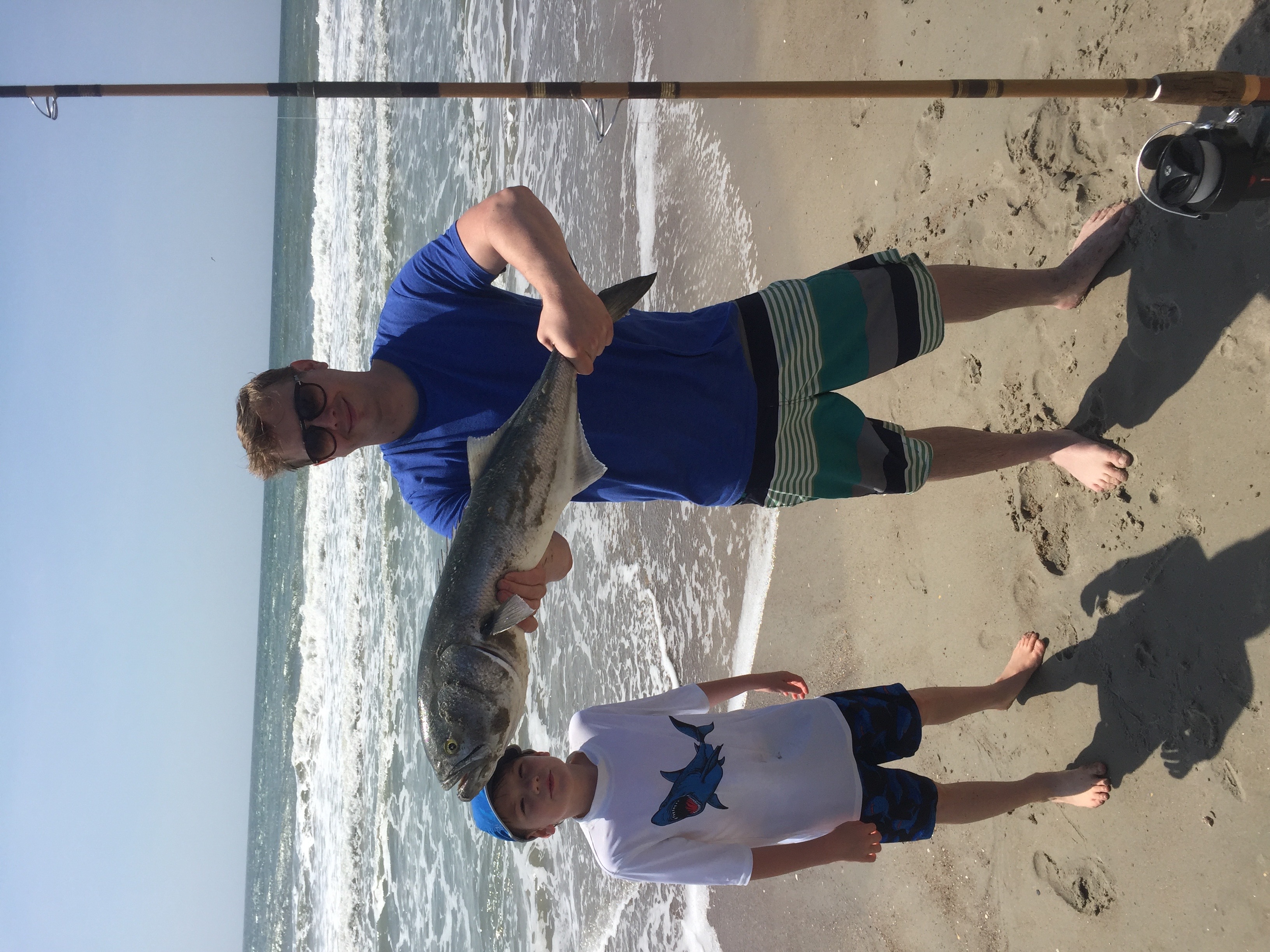 Surf fishing holding a blue fish.