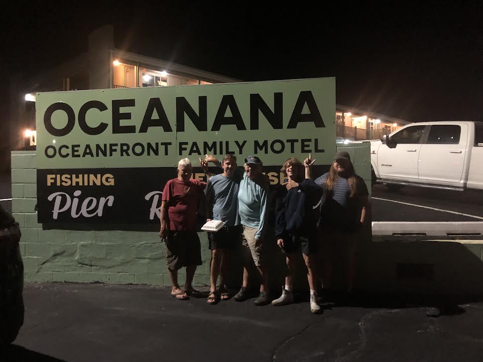 Group posing in front of a sign at night.