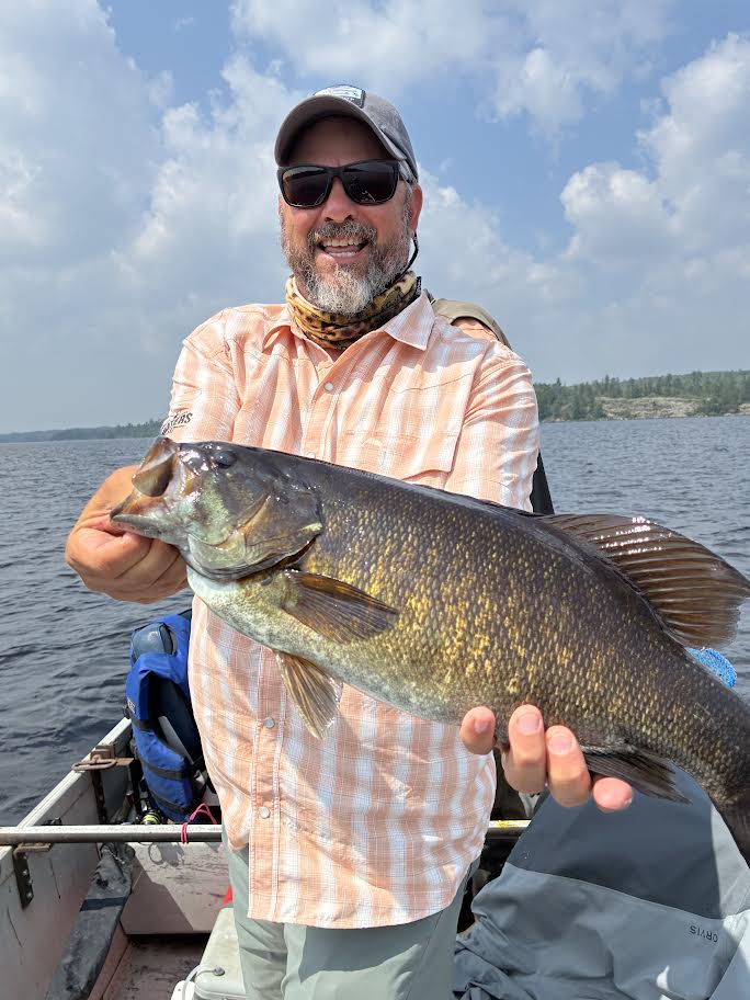 Man in an orange shirt holding a fish.