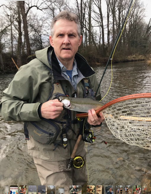 Man in wadders holding fish by the river.