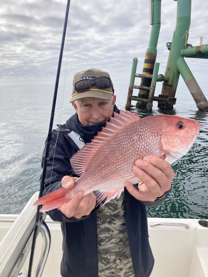 Man holding a pink fish he just caught.