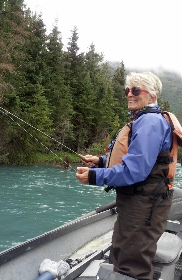 Woman smiling and fishing from a boat.